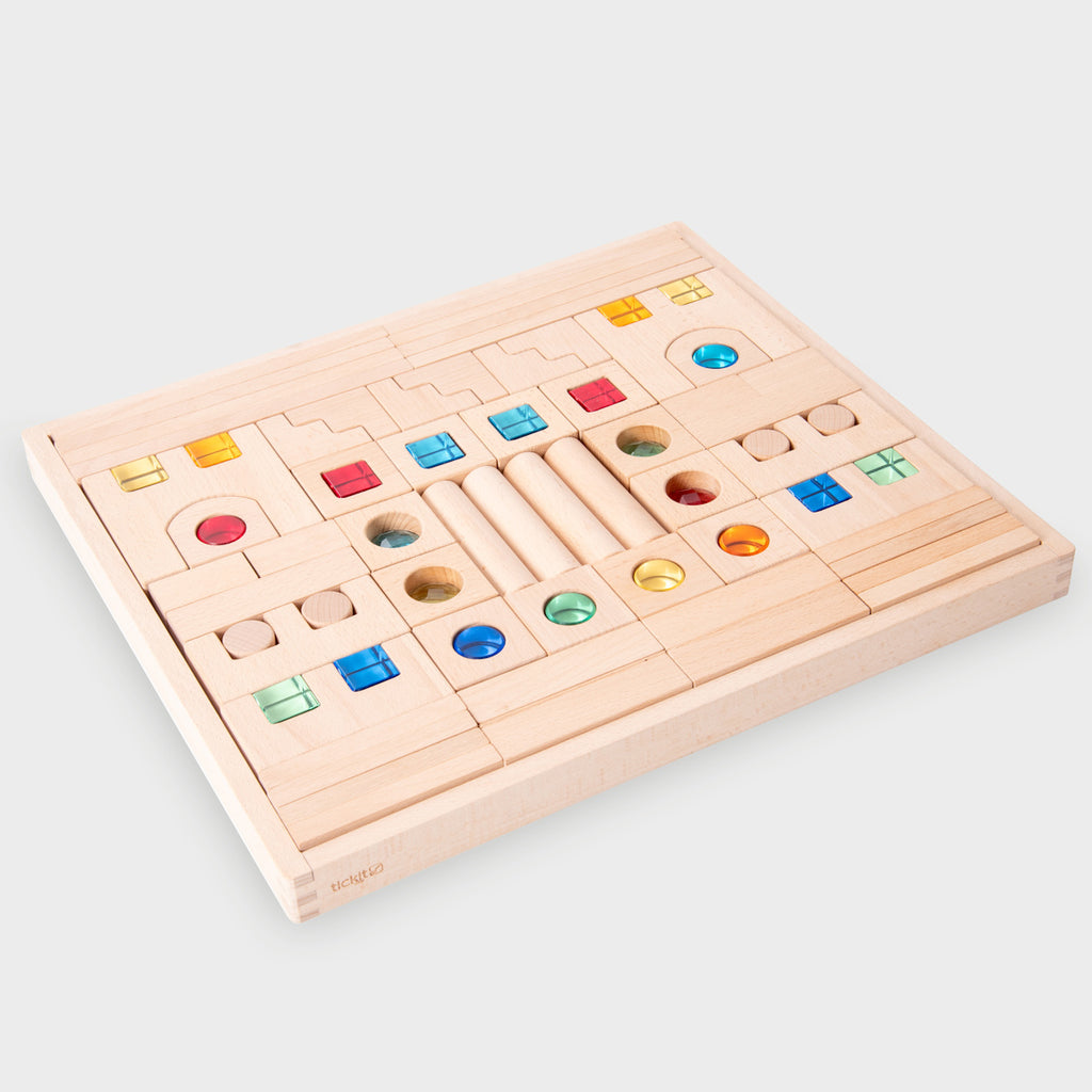 A large collection of wooden construction blocks with embedded colorful gems, designed to encourage creative building, light play, and sensory exploration.