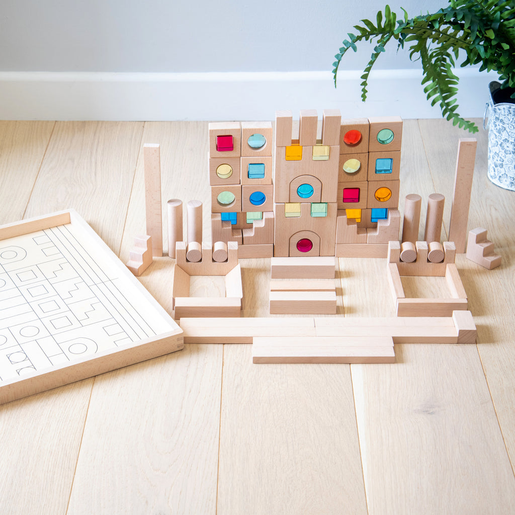A large collection of wooden construction blocks with embedded colorful gems, designed to encourage creative building, light play, and sensory exploration.