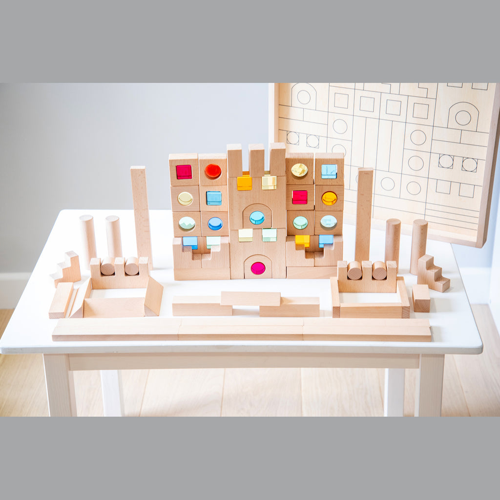 A large collection of wooden construction blocks with embedded colorful gems, designed to encourage creative building, light play, and sensory exploration.