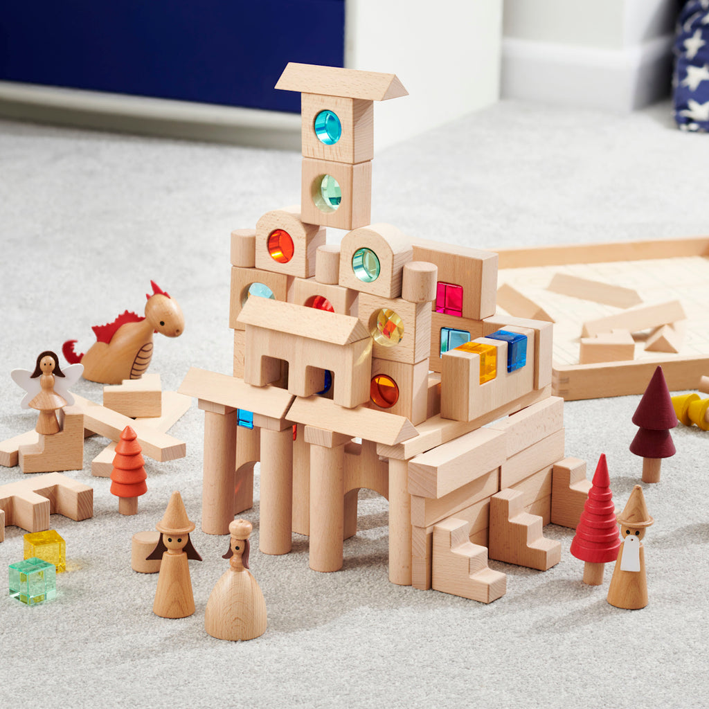 A large collection of wooden construction blocks with embedded colorful gems, designed to encourage creative building, light play, and sensory exploration.