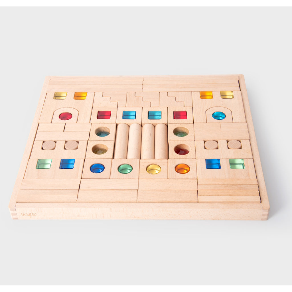 A large collection of wooden construction blocks with embedded colorful gems, designed to encourage creative building, light play, and sensory exploration.