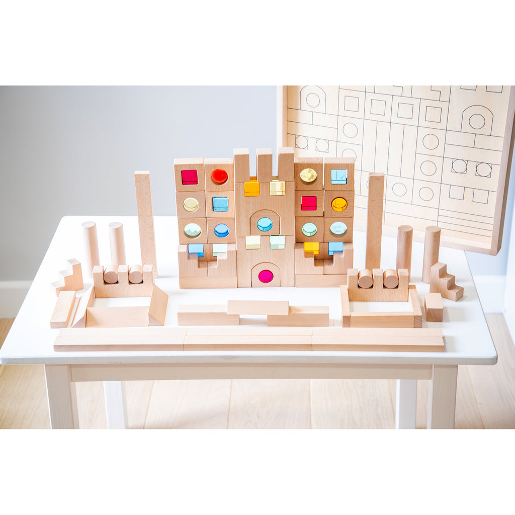 A large collection of wooden construction blocks with embedded colorful gems, designed to encourage creative building, light play, and sensory exploration.