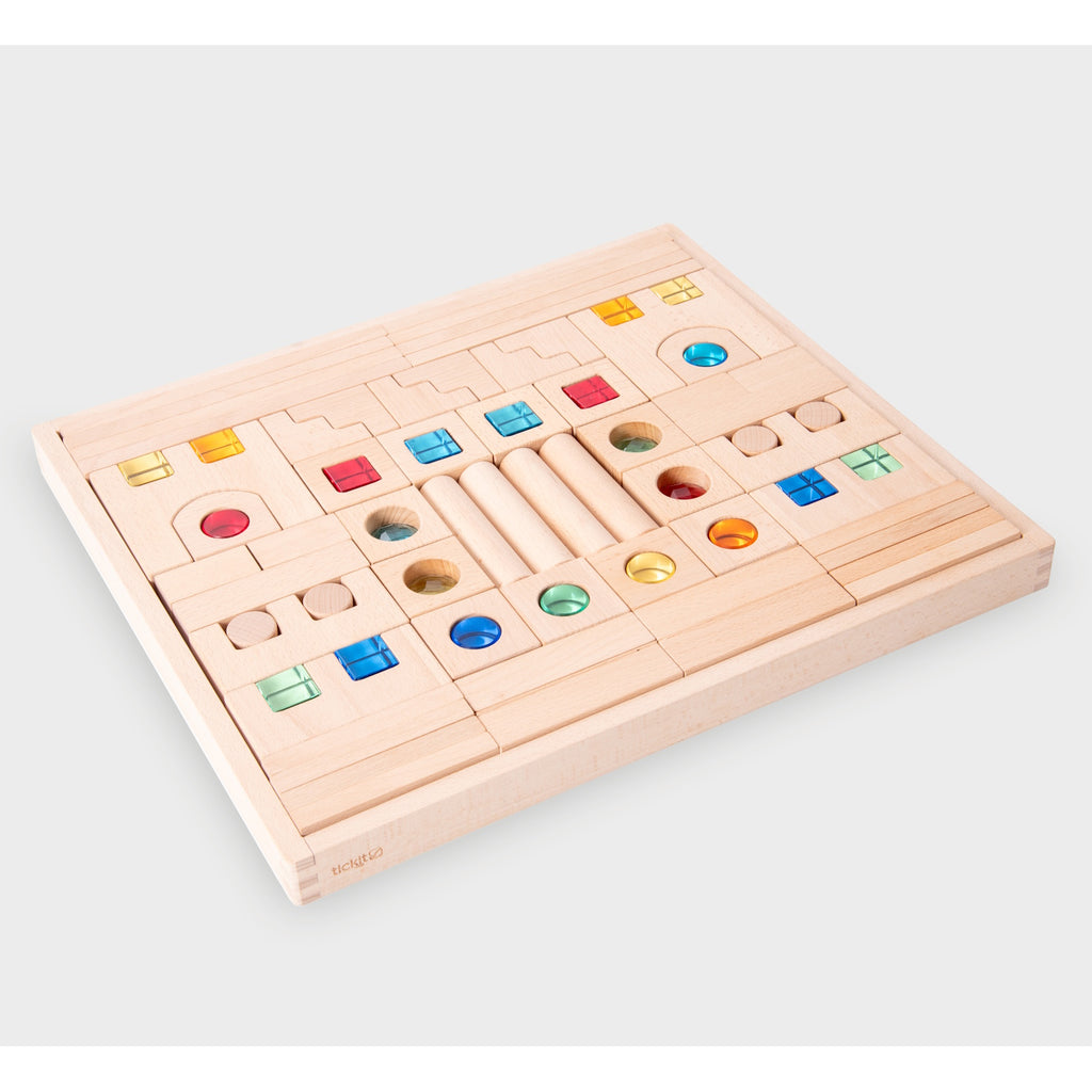 A large collection of wooden construction blocks with embedded colorful gems, designed to encourage creative building, light play, and sensory exploration.