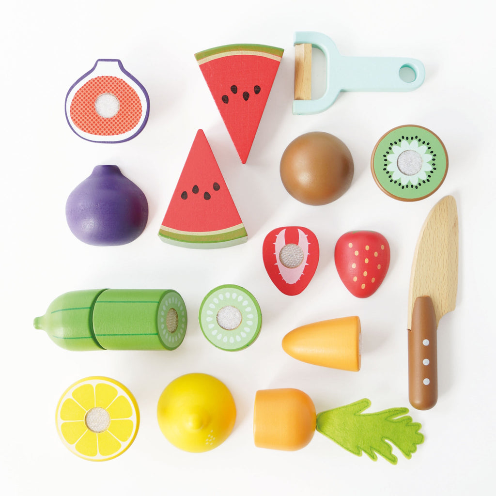 Colorful wooden toy fruits and vegetables, including watermelon, kiwi, orange, and lemon slices with a toy peeler and knife on a white background.