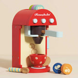 A colorful wooden toy coffee machine with a polka-dot cup, spoon, and coffee pods.