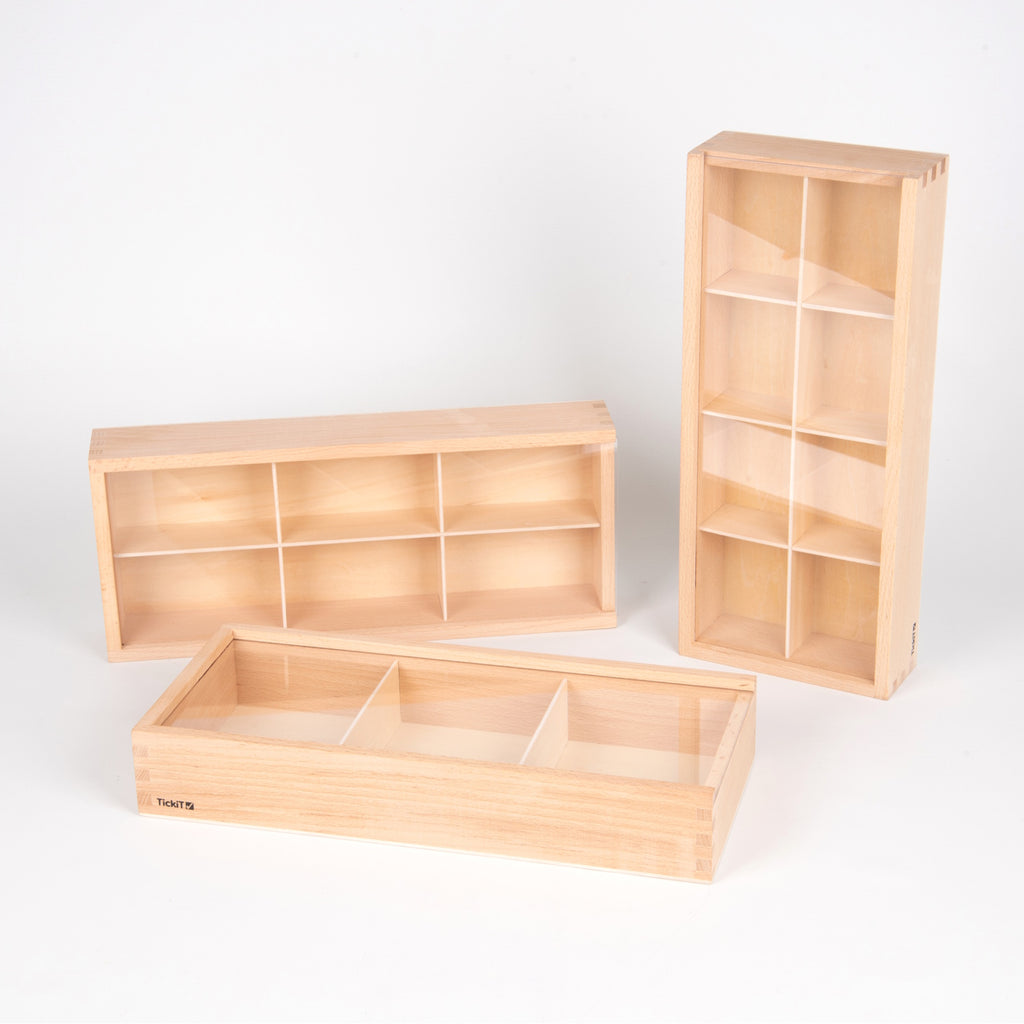 A set of natural wooden boxes with various openings and textures, designed to encourage sensory exploration and fine motor development in young children.