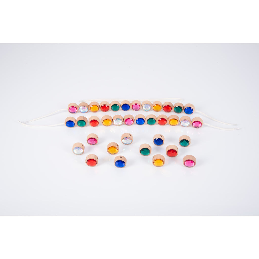 A set of brightly colored wooden gem-shaped beads with holes for threading, designed to develop fine motor skills and hand-eye coordination.