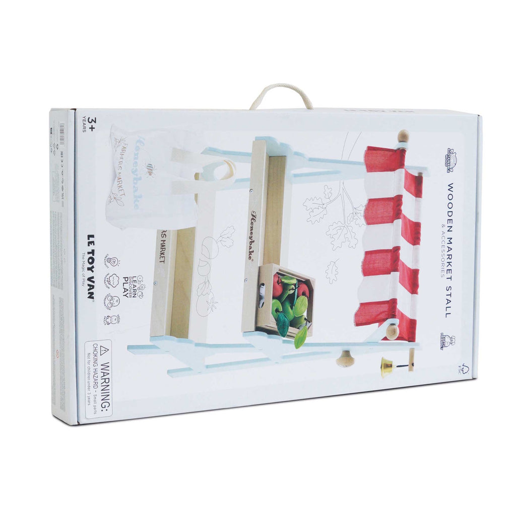 Box for a wooden market stall toy by Le Toy Van. Features bright red and white stripes, a small bell, and colorful vegetables, conveying a playful theme.