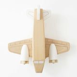 Top-down view of a natural wooden toy airplane with white painted engines and tail fin.