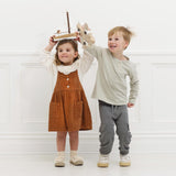 Two children happily playing together holding a wooden toy sailboat and a wooden toy plane.