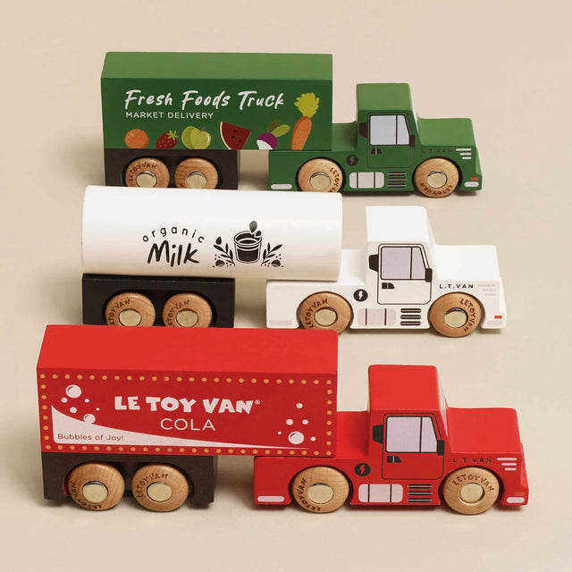 Three colorful wooden toy trailer trucks in green, white, and red with wooden wheels.