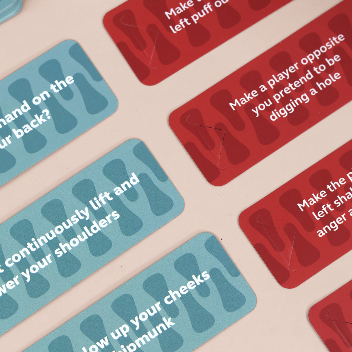 Red and blue party game cards with printed action prompts on a light surface.