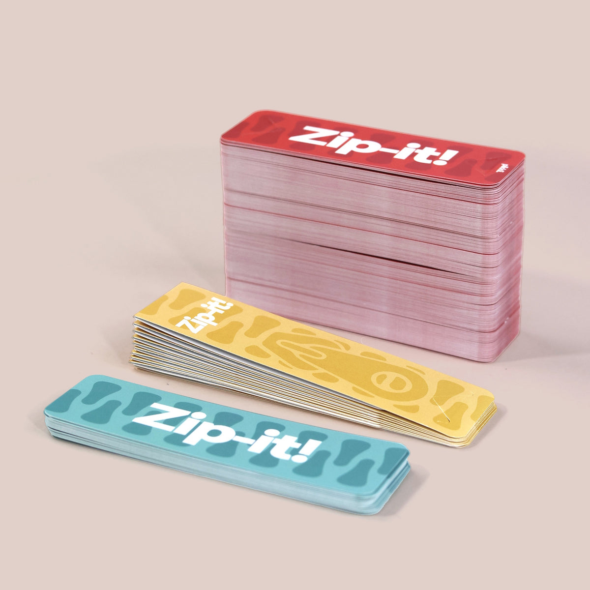 Stacked colorful Zip-it! game cards in blue, yellow, and red on a neutral background.