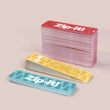 Stacked colorful Zip-it! game cards in blue, yellow, and red on a neutral background.