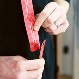 Close-up of hands connecting red game cards, reading "Make the oldest player pretend to be a kangaroo".