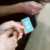Hands holding a small deck of Zip-it! game cards with a light blue card on top.