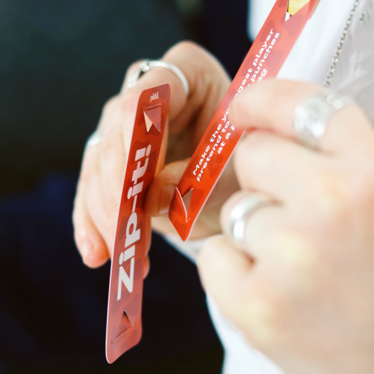 Close-up of a person holding red Zip-it! game cards during play.
