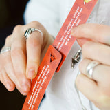 Close-up of hands connecting red Zip-it! game cards together using built-in tabs.