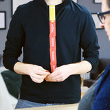 Person in a black long-sleeve shirt holding connected red and yellow game cards vertically.