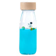 A clear sensory bottle with a wooden cap, filled with blue liquid, a floating astronaut figurine, and silver star-shaped confetti.