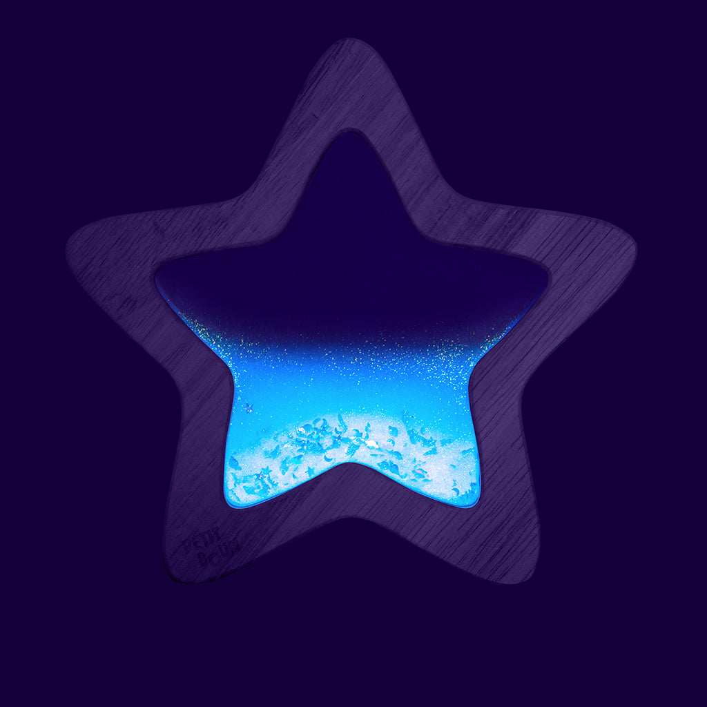 The Flow Star sensory toy glowing in the dark, revealing its sparkling and luminescent effect.